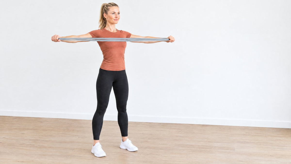 Woman doing a band pull apart with a light grey resistance band, arms open to the sides at shoulder height (AI)