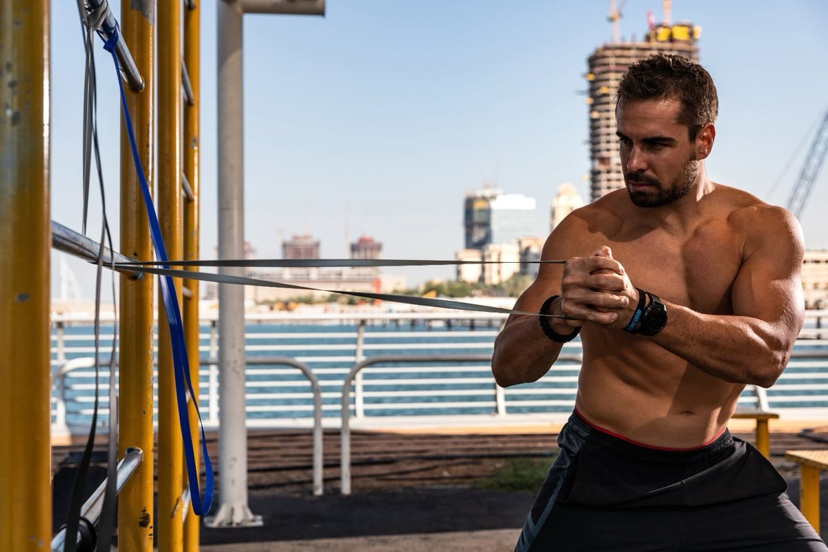 Athlete holding an aerobis Powerband at his chest in the start position of a Pallof press by the waterfront