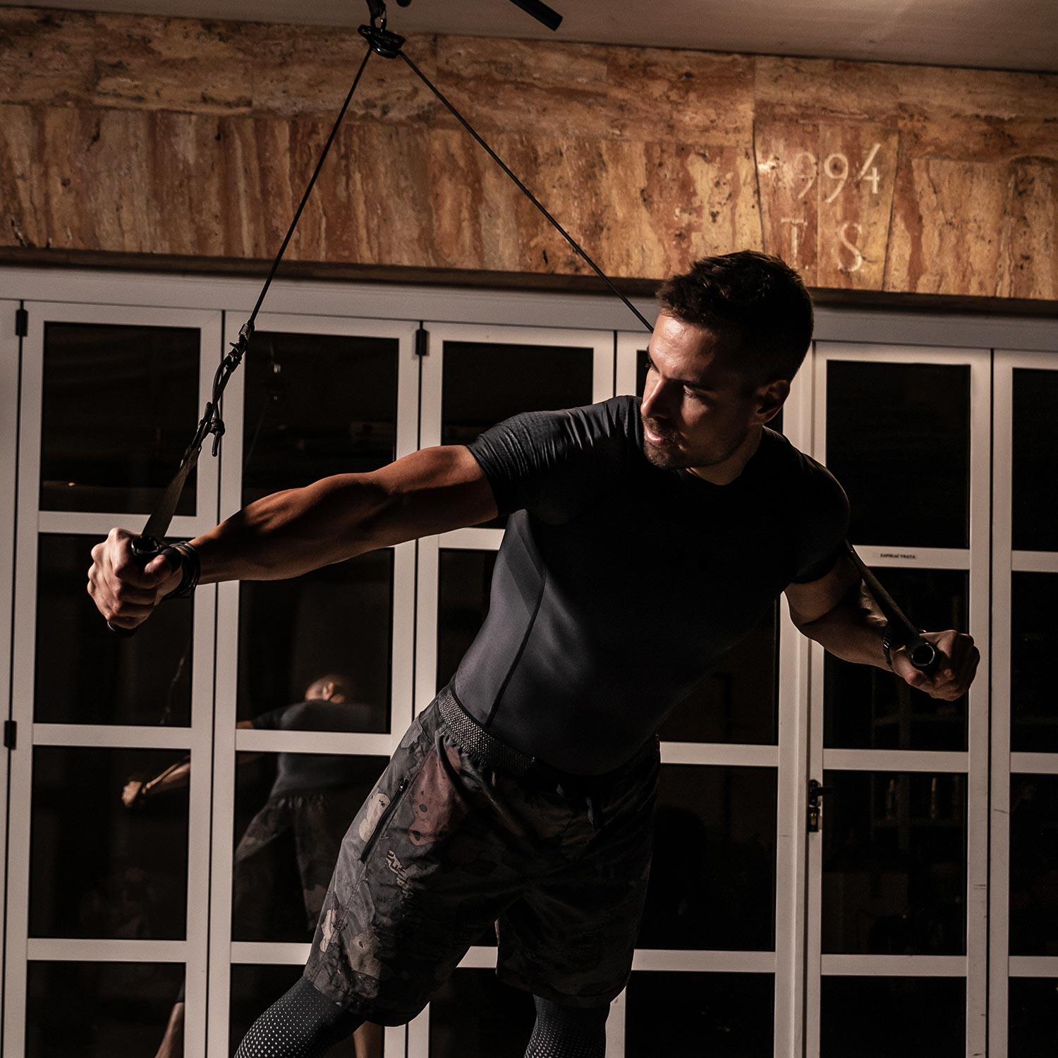 Male athlete performing a strap-based chest press with the aerobis aeroSling Tactical Slingtrainer indoors