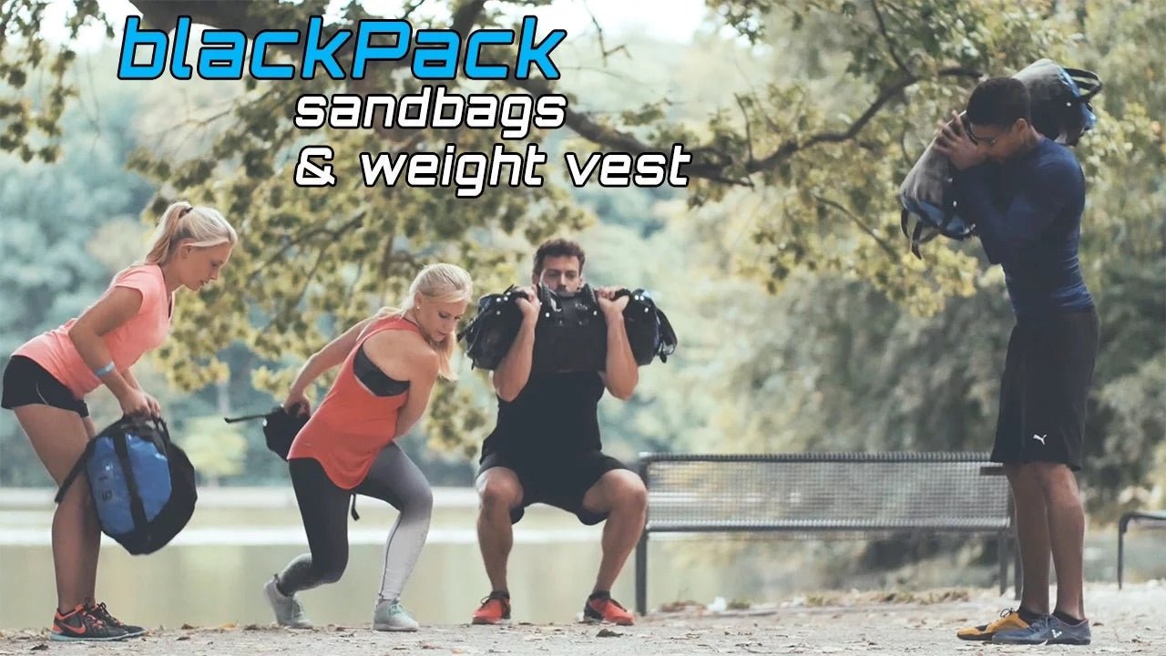 Group training outdoors with sandbags and weight vests near a lake.