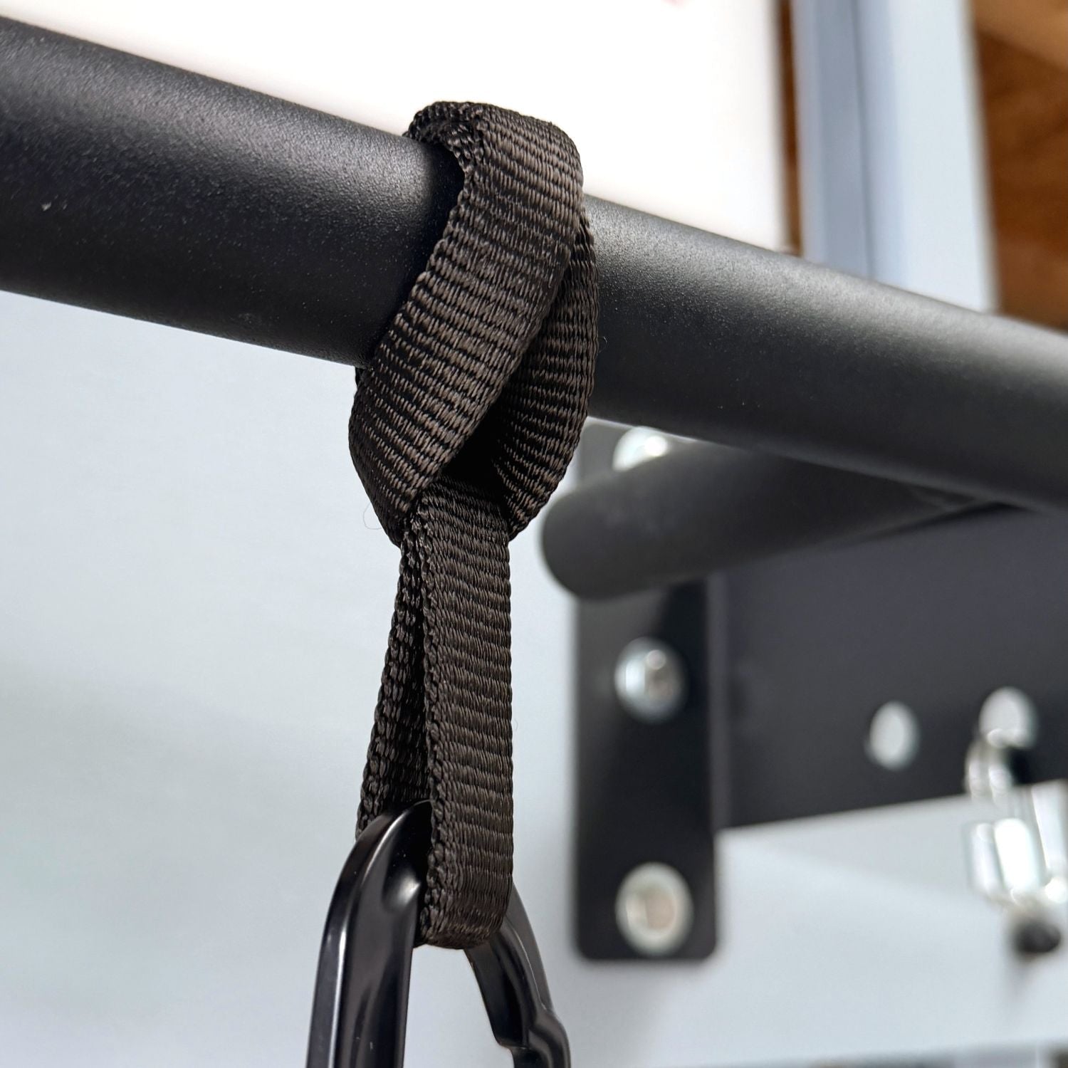 aerobis Mini Sling attached to a pull-up bar with a carabiner for space-saving suspension