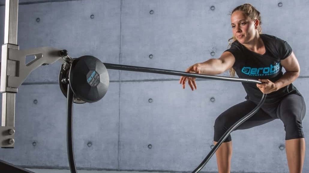 Eine Frau führt mit dem revvll PRO-Trainer Übungen mit dem Widerstandsseil durch.