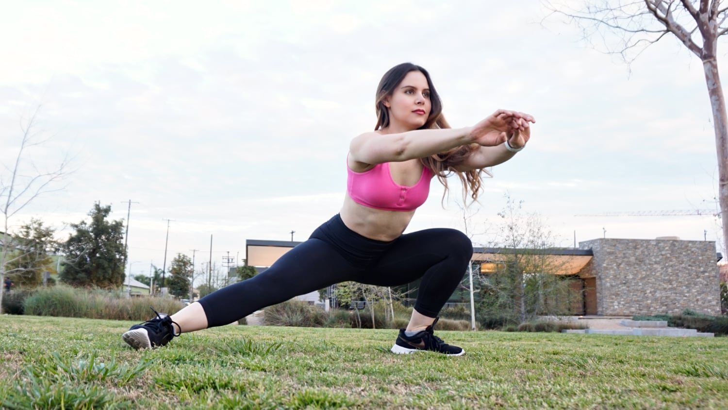 Eine Frau macht seitliche Ausfallschritte auf dem Rasen für das Fitnesstraining im Freien.