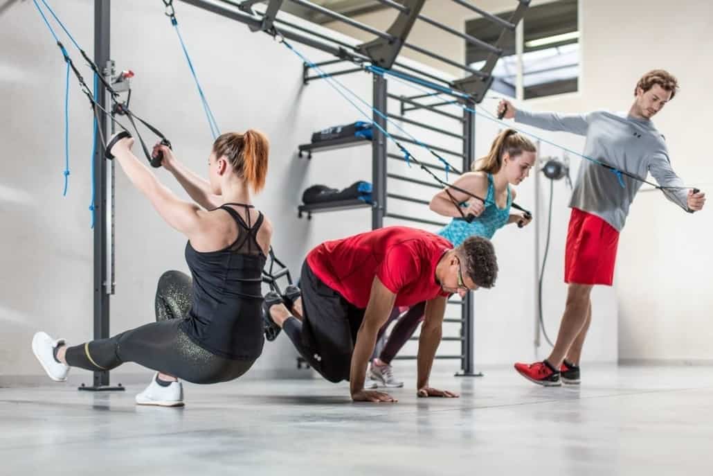 Gruppo di persone che si allenano con le imbragature in una palestra di fitness funzionale.