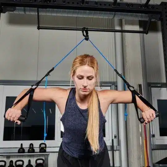 Vrouw doet borstoefeningen met suspension trainer in een sportschool.